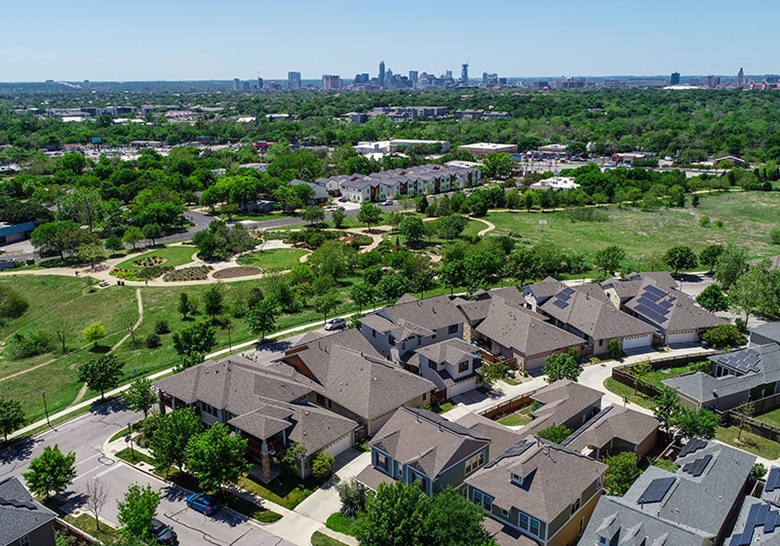 Overhead view of houses with solar panels on rooftops and downtown buildings in background